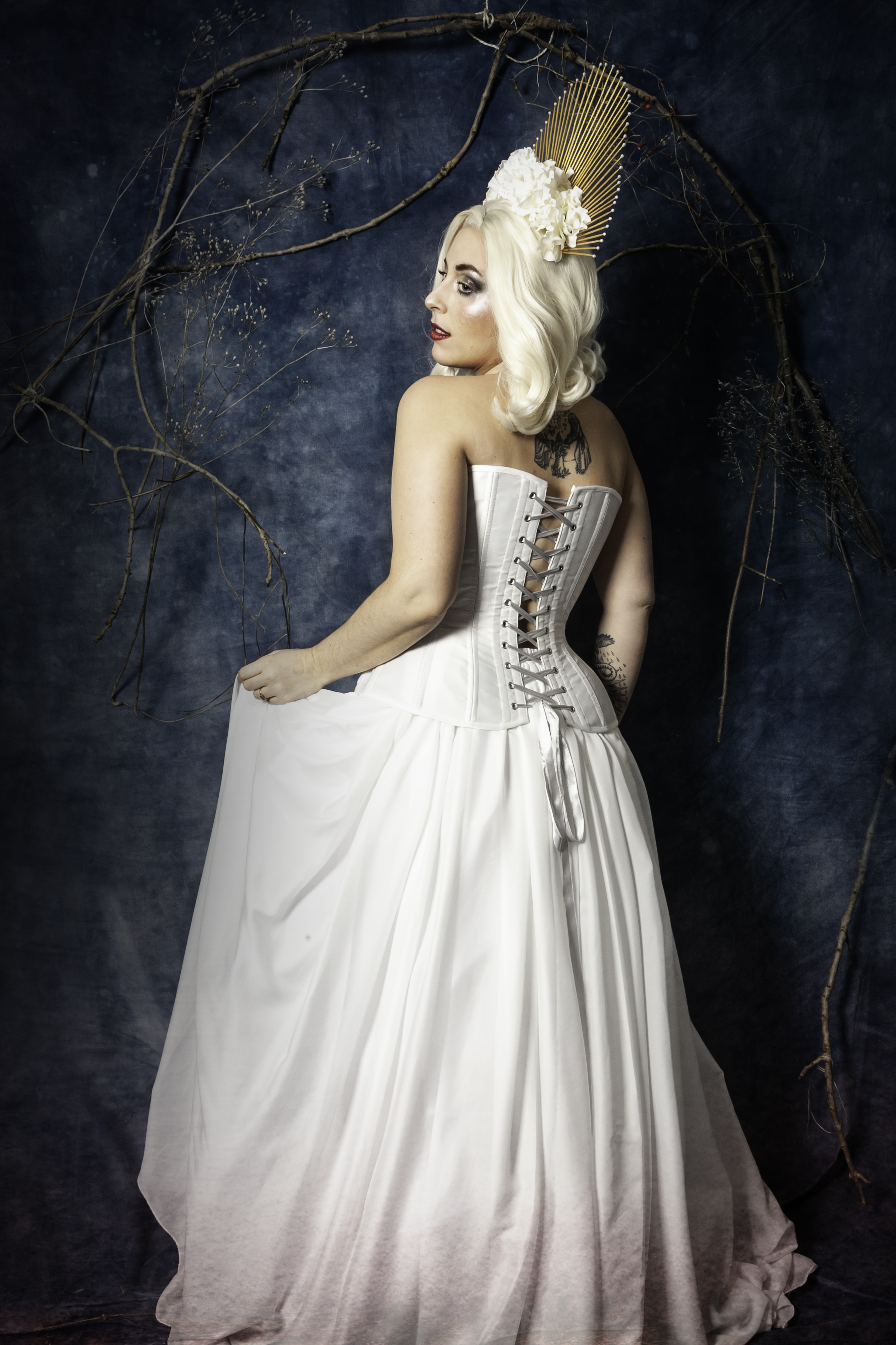 Corset blanc et dentelle, coiffe dorée, fleurs et perles blanches.