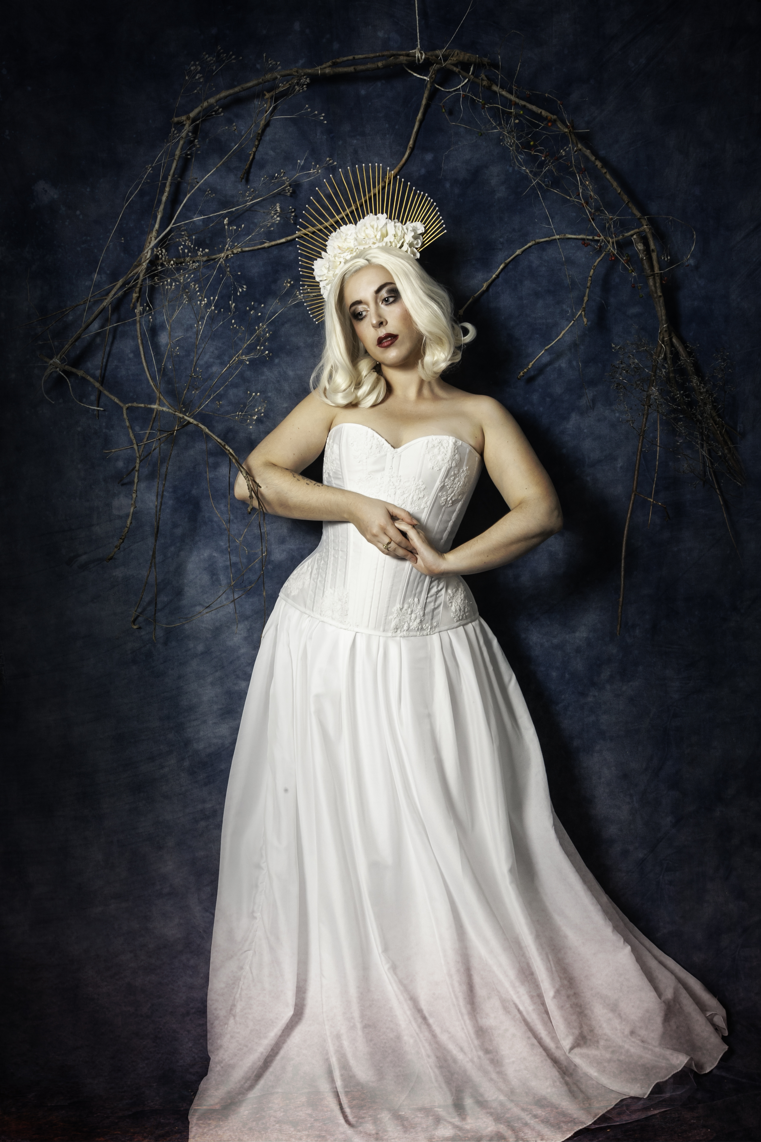 Corset blanc et dentelle, coiffe dorée, fleurs et perles blanches.