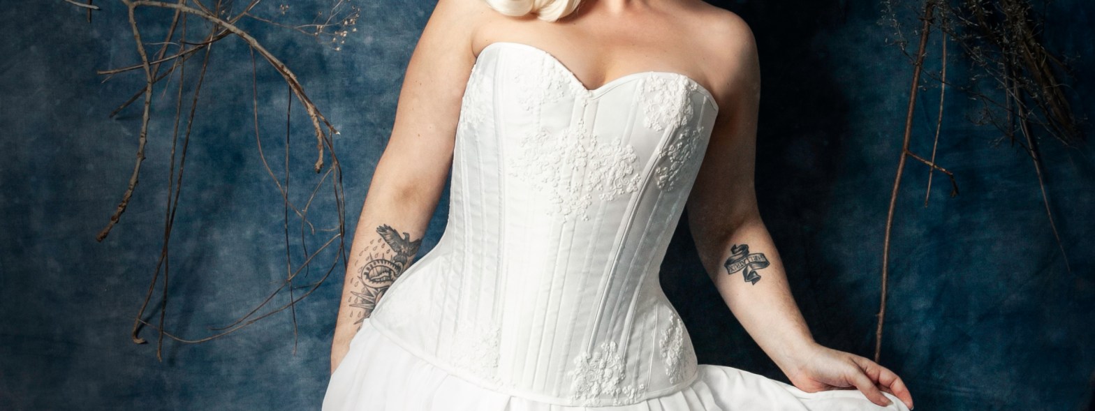 Corset blanc et dentelle, coiffe dorée, fleurs et perles blanches.