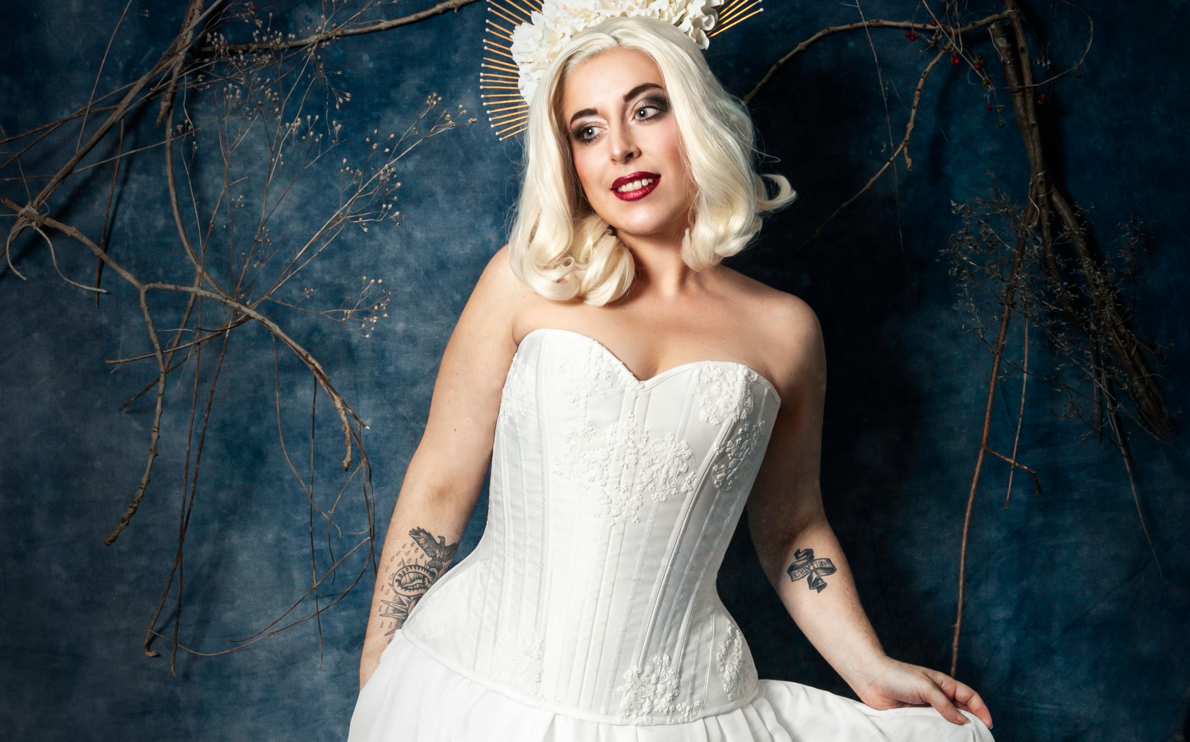 Corset blanc et dentelle, coiffe dorée, fleurs et perles blanches.