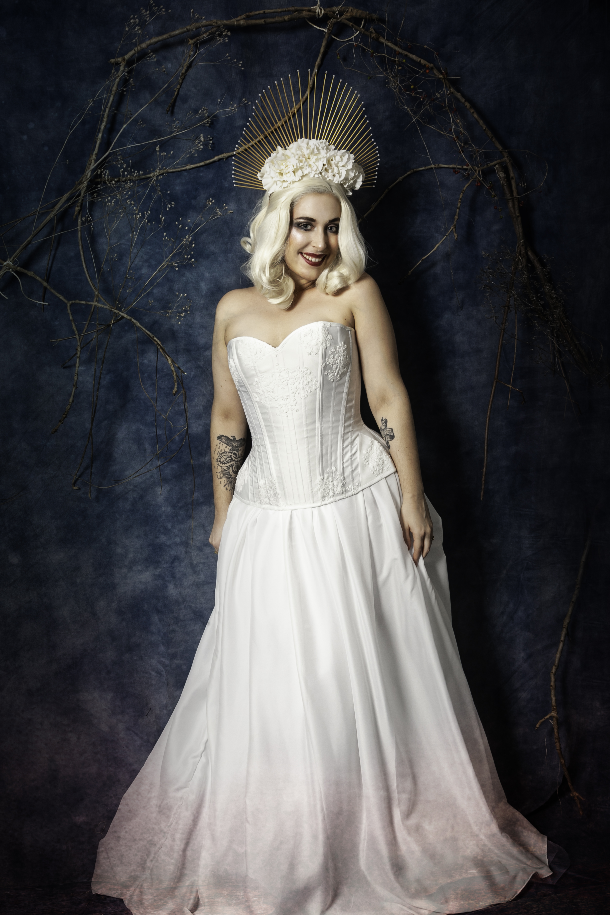 Corset blanc et dentelle, coiffe dorée, fleurs et perles blanches.